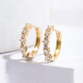 Nahaufnahme von goldenen Creolen mit blauen Zirkonia Einlagen auf weißem Hintergrund - Weißer Zirkonia / Gold
