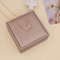 Macro detail of a golden butterfly pendant with clear glass wings on a jewelry box - White