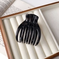 Dettaglio di una grande molletta per capelli nera lucida in un portagioie di velluto beige - Nero Lucido