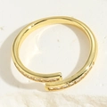 Dettaglio di un anello aperto placcato oro con pietre di zircone su base bianca testurizzata - Anello con Design a Croce