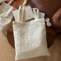Macro view of beige lace embroidery texture and vintage tag on a cotton tote bag - Cotton Thread Flower Embroidery