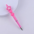 Detailed close-up of a DIY pink floral beaded pen with colorful silicone charms on a white base - Rose Red
