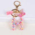 Glitter resin initial H keychain with pink tassel and butterfly charm in gold finish - Letter H
