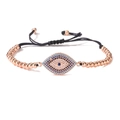 Detail of rose gold evil eye bracelet featuring blue cubic zirconia and black woven cord - Rose Gold (Multicolor)