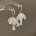 Vista macro di orecchini a fiore bianco con nappine di perle e dettagli in metallo oro - Stile Perlato 3D con Grande Fiore Bianco