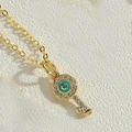 Macro shot of gold key pendant necklace featuring evil eye charm and crystal pave details - Dark Green Key
