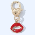 Dettaglio di un ciondolo a labbra in smalto rosso con strass su un portachiavi dorato lucido - Labbra con due brillantini
