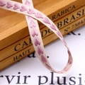 Macro detail of cream cotton ribbon with pink heart embroidery on vintage wooden box - 10mm / Deep Pink