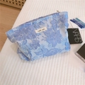 Dettaglio della borsa cosmetica in pizzo blu con ricamo 3D ed etichetta Simple Wish - Blu