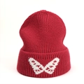 Detail of dark red knit beanie showing white butterfly jacquard pattern on ribbed cuff - One Size (Elastic) / Red