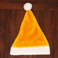 Yellow and white plush Christmas hat with white pom-pom on dark wood background - Orange