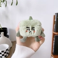 Close-up of green plush earphone case with cute cartoon face for AirPods Pro protection - Green Plush Monster Staring Expression / AirPods 1/2 Gen
