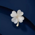 Elegant gold four-leaf clover brooch with pearly opal stones on a textured blue surface - Gold White Cat Eye Clover