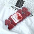 Close-up of red heart-shaped tea lights with glitter in clear box on white fabric - Red