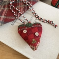 Detail of red knitted heart ornament with wood buttons on a decorative book - Heart Style