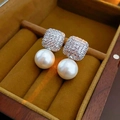Close-up of square zircon pearl earrings on yellow velvet cushion in a wooden jewelry box - 925 Silver Pin Square Zirconia Pearl Style / Silver