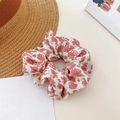 Pink floral print fabric scrunchie with white base on a minimalist desk background - Rose Red