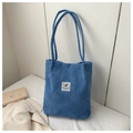 Gros plan du sac fourre-tout en velours côtelé bleu avec texture tissée et étiquette - Bleu