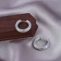 Silver hinged hoop earrings with a textured woven pattern displayed on wood - E-086---Platinum