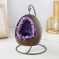 Egg-shaped night light with purple crystals on a black stand with white power cord - Dinosaur Egg Night Light - Amethyst Teeth