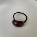 Dettaglio di un elastico per capelli bordeaux con decoro ovale in resina per look chic - Viola Uva