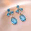 Elegant gold drop earrings with sky blue stones on champagne silk background - Sky Blue Water Drop Pendant Style (E0854)
