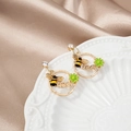 Detailed macro view of gold bee earrings with green flowers and Queen engraving - Gold Bee Flower Queen Hoop Dangle