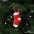 Mini calza di Natale fatta a mano all'uncinetto in rosso e bianco su rami di un pino - Calza di Natale