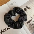 Elegant black faux leather scrunchie with pleated design on a minimalist background - Black