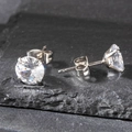 Detailed macro view of 8mm round-cut cubic zirconia stud earrings with 4-prong setting - 8mm / Silver