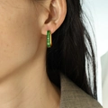 Elegant gold earrings with square-cut emerald green zircons on a female model - Green Rectangular Zirconia Huggie / Green