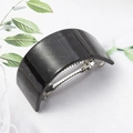 Detail of dark grey curved hair clip showing the internal metal spring and stone texture - Black