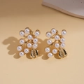 Dettaglio di orecchini a fiore dorati vintage con eleganti perle bianche su beige - Orecchini a Fiore con Perle di Imitazione (Perno in Argento S925) / Oro