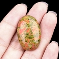 Handheld oval polished Unakite gemstone with natural green and pink mineral texture - Unakite