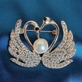 Macro shot of rose gold double swan brooch with crystal pave and a white pearl detail - Love Swan Brooch