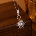 Macro di una collana con ciondolo a sole argento e zirconi su una scatola per gioielli - Collana Sole Stella Colore Acciaio