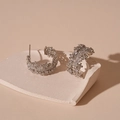 Detailed view of silver C-shaped hoop earrings with zircon pavé on a beige tray - Zirconia C-Shape Studs / Silver