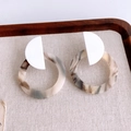 Dettaglio di orecchini tondi in resina traforata con trama a tartaruga e perni bianchi - Giunzione di Marmo Bianco (Perno per orecchini in argento)