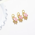 Three gold oval pink zircon charms for jewelry making shown on a reflective surface - Pink