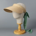 Detail of raffia sun visor with long green ribbon bow on mannequin head with wooden base - M (56-58cm) / Natural + Green Ribbon