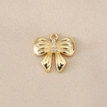 Macro view of gold bow pendant with three inlaid zircons on a beige silk texture background - Vertical Three Stone Bow (PJ0161) / Gold