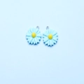 Detail shot of light blue daisy flower resin charms with yellow centers and silver rings - Lake Blue