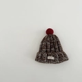 Detail der grob gestrickten braun-weißen Textur mit rotem Bommel und gewebtem Etikett - Ca. 2-4 Jahre / Braun