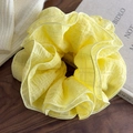 Macro detail of a 4-layer ruffled yellow scrunchie on a wooden surface in a cozy home setting - Yellow