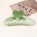 Close-up of light green heart hair claw clip on a Vogue magazine background - Heart Hollow Semicircle / Light Green