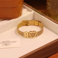 Détail d'un bracelet en maille dorée avec un charme lettre R et une icône de cœur - Lettre R