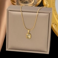 Detail shot of a gold butterfly pendant with a light blue gem in a beige jewelry box - Blue/White Rhinestone Pendant (H616)