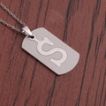 Vue macro d'un collier en acier inoxydable avec pendentif S sur surface bois sombre - Lettre S