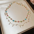 Detailed macro view of double-layered gold necklace with colorful flower beads and white pearls - Double Layer Tassel Style / Gold-Multicolor