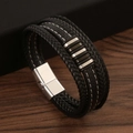 Close-up of black braided leather bracelet with metal accents on wooden surface - Black & Silver